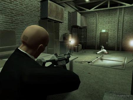 Hitman: Blood Money screenshot: Agent 47 aims a gun at a target in a dimly lit, industrial-style room.