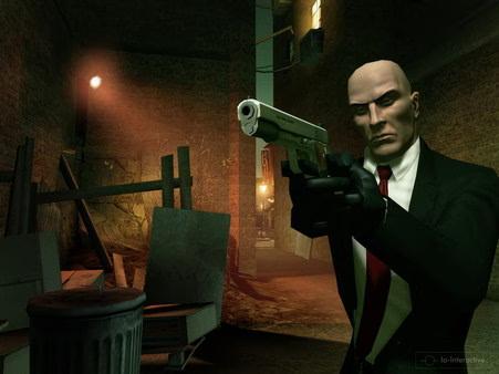 Hitman: Blood Money screenshot. A suited character aims a silenced pistol in a dimly lit alley, surrounded by debris.
