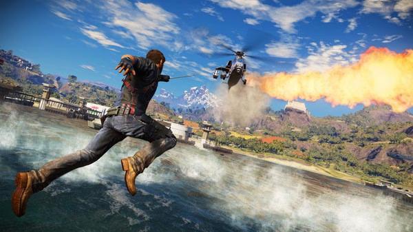 Just Cause 3 screenshot: A character uses a grappling hook to chase a helicopter shooting flames over a coastal area.