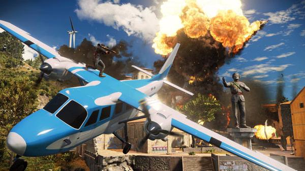 Screenshot from Just Cause 3 showing a character standing on a blue plane, with an explosion and statue in the background.