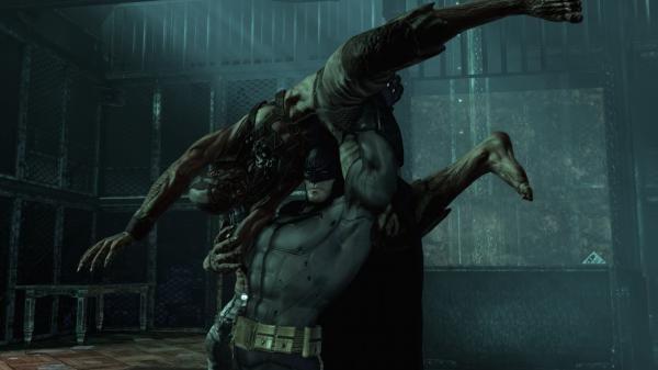 Batman: Arkham Asylum screenshot showing Batman lifting a creature in a dimly lit room with metallic walls and a grated floor.