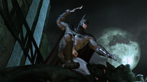 Batman: Arkham Asylum screenshot. Batman crouches on a gargoyle, ready to throw a batarang, with a full moon illuminating the scene.