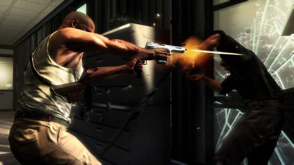 Max Payne 3 screenshot: A tense shootout scene shows a character firing a handgun at an enemy near shattered glass in an office setting.
