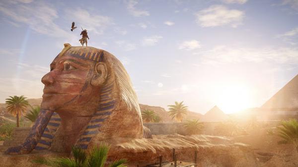 Screenshot from Assassin's Creed Origins showing a character standing on a giant Sphinx with pyramids in the background.