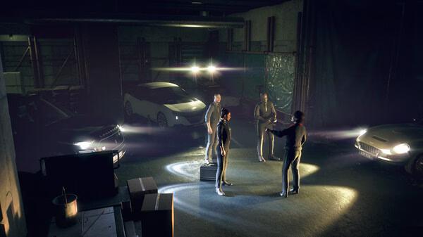 A Watch Dogs: Legion screenshot showing four characters in a dimly lit garage surrounded by cars and boxes, engaged in conversation.