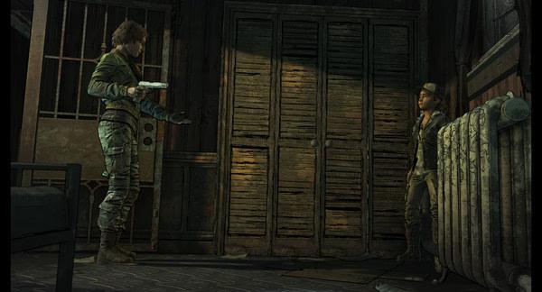 Screenshot from The Walking Dead: The Telltale Definitive Series showing two characters in a tense standoff near a wooden wardrobe.