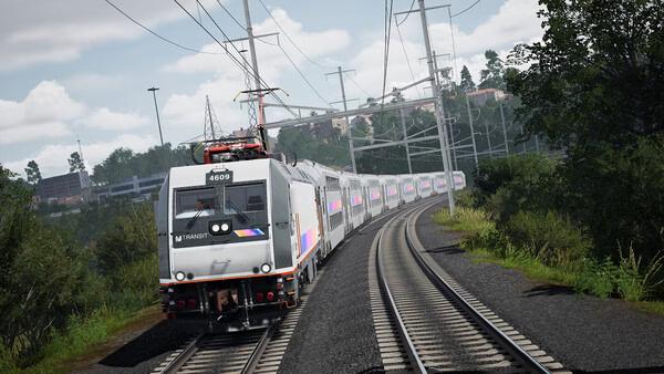 Train Sim World 6 screenshot showing a modern passenger train traveling through a scenic forested area on curved railway tracks.