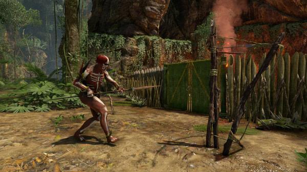Screenshot from Green Hell showing a character in tribal attire pulling a lever next to a wooden fence in a jungle setting.