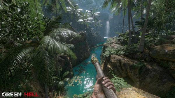 A Green Hell screenshot showing a player's hand holding a spear, overlooking a jungle river surrounded by lush vegetation and a waterfall.