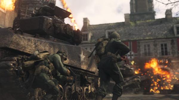 Call of Duty: WWII screenshot showing soldiers advancing beside a tank in a war-torn village with explosions in the background.