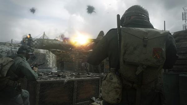 A Call of Duty: WWII screenshot showing soldiers in combat near sandbags as a plane crashes in the background.