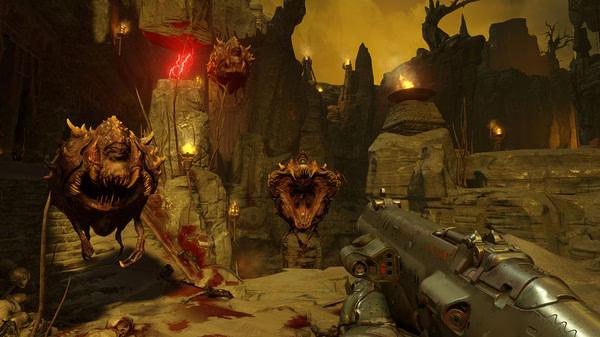 A DOOM screenshot showing a player aiming a shotgun at floating demon enemies in a fiery, rocky landscape with torches.