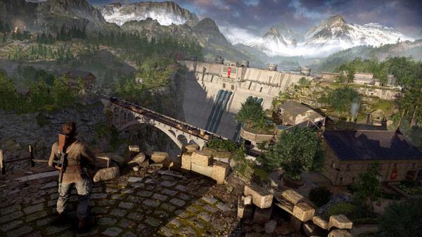 Sniper Elite: Resistance screenshot: A soldier kneels, overlooking a dam and surrounding landscape with mountains in the distance.
