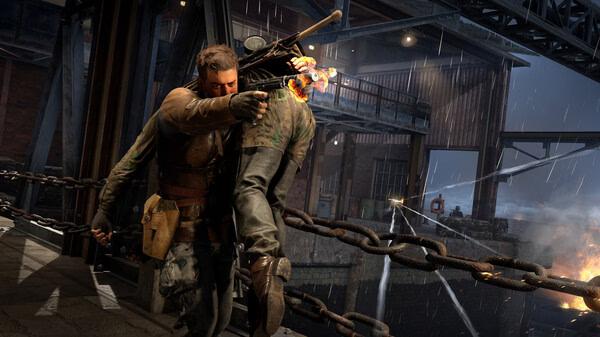Screenshot from Sniper Elite: Resistance showing a soldier carrying another under fire on a rainy bridge.