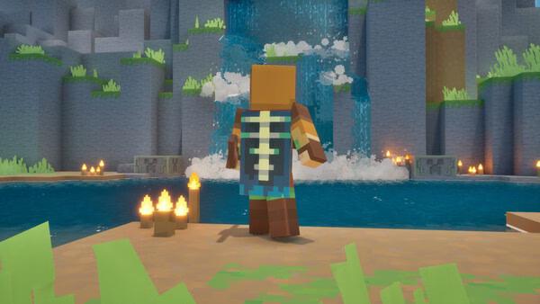 A Minecraft Dungeons II screenshot showing a character standing by a waterfall, surrounded by grass, candles, and a calm pool.
