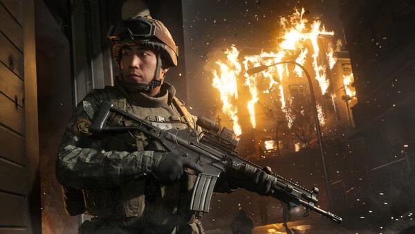 A soldier holding a rifle stands alert in a war-torn city with burning buildings in this Call of Duty®: Modern Warfare® 4 screenshot.