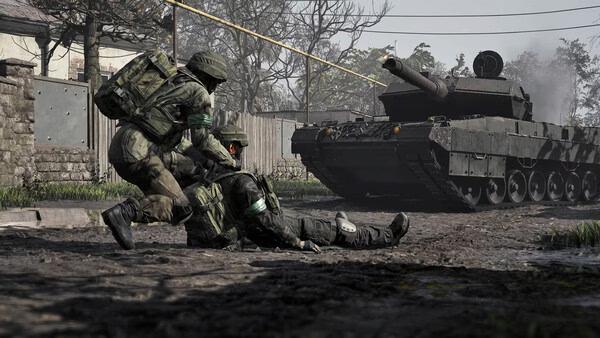 Two soldiers in combat gear assist an injured comrade near a tank in a WARDOGS game screenshot showing a war-torn environment.