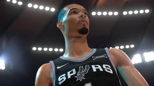 A screenshot from NBA 2K27 showing a close-up of a Spurs player under bright arena lights, wearing a black jersey.