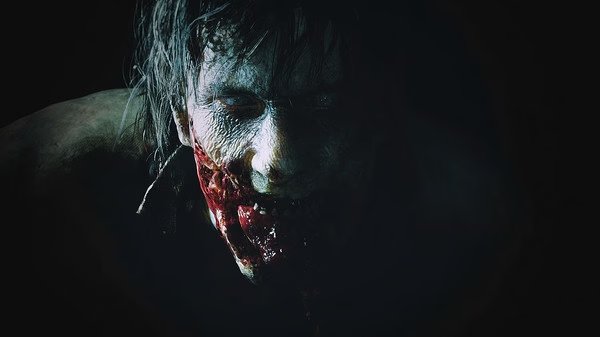 Resident Evil 2 screenshot: A zombie emerges from the shadows, showcasing the game's intense horror atmosphere.
