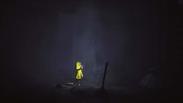 Screenshot from Little Nightmares showing a character in a yellow raincoat standing in a dark, eerie room with scattered debris.
