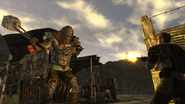 Screenshot from Fallout: New Vegas showing a character firing at a large mutant wielding a sledgehammer in a desert setting.