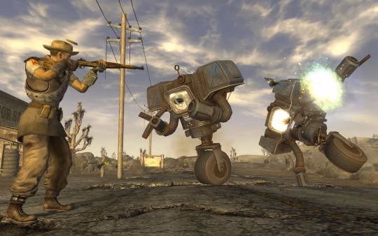Screenshot from Fallout: New Vegas showing a character aiming a rifle at two robots on a deserted road under a cloudy sky.