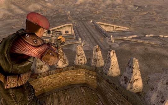 Screenshot from Fallout: New Vegas showing a character in a red beret aiming a sniper rifle from a wooden tower overlooking a desert landscape.