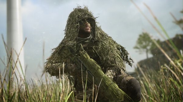 A Call of Duty®: Modern Warfare® II screenshot shows a soldier in a ghillie suit crouched in tall grass, holding a weapon.