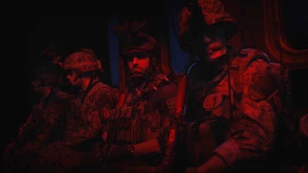 Screenshot from Call of Duty®: Modern Warfare® II showing soldiers in tactical gear seated inside a dimly lit military transport.