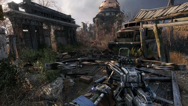 Screenshot from Metro Exodus showing a detailed crossbow in the foreground with a post-apocalyptic landscape and abandoned vehicles.