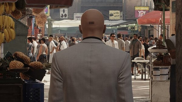 HITMAN World of Assassination screenshot: Agent 47, in a white suit, walks through a bustling outdoor market.