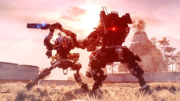 Titanfall® 2 screenshot showing two towering Titans engaged in combat against a vibrant sunset backdrop with rocky terrain.
