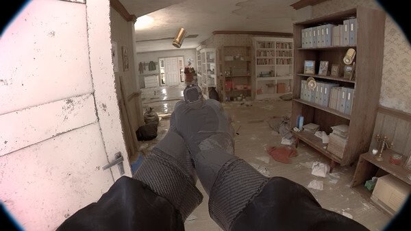 Screenshot from 'Unrecord' showing a first-person perspective of hands holding a gun in a cluttered, dimly-lit room with shelves and scattered items.