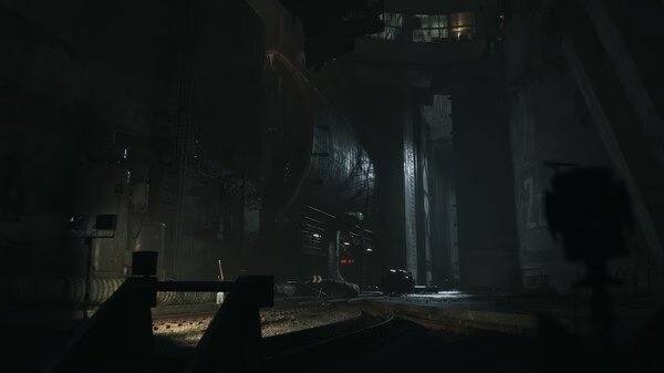 A screenshot from the game ILL showing a dark, industrial environment with large machinery and dim lighting.