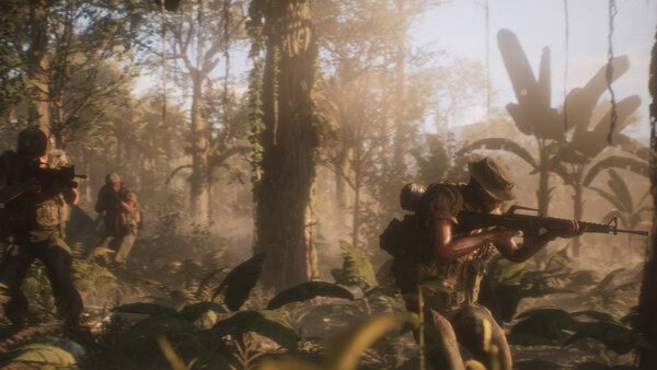Screenshot from Hell Let Loose: Vietnam showing soldiers advancing through a dense jungle, armed with rifles, under dappled sunlight.