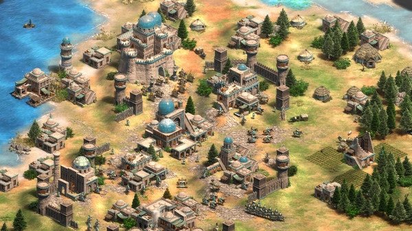 Screenshot from Age of Empires II showing a bustling medieval town with various buildings and units by the sea.