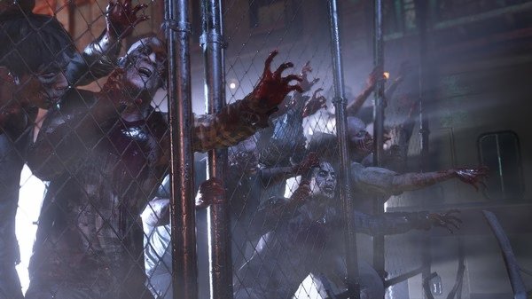 Resident Evil 3 screenshot: Zombies aggressively reach through a chain-link fence, illuminated by eerie lighting.