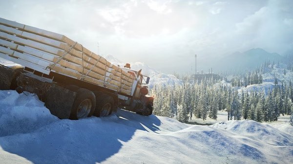 SnowRunner screenshot: A large truck navigates through a snowy landscape with distant mountains and trees under a bright sky.