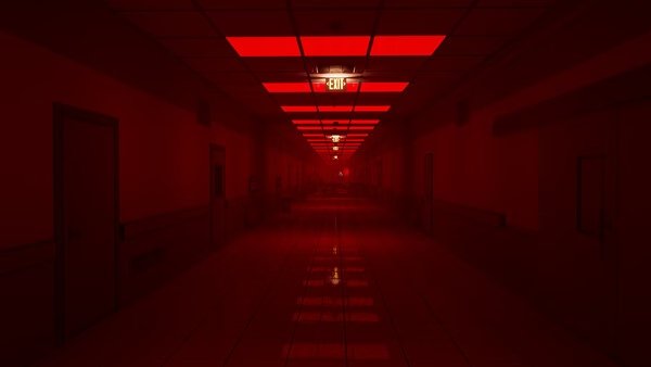 A screenshot from Escape the Backrooms showing a long, eerie hallway lit by red lights and an illuminated exit sign in the distance.