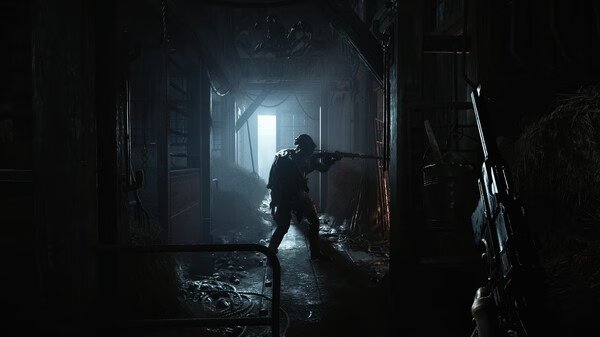 A Hunt: Showdown 1896 screenshot showing a player aiming a weapon in a dimly lit barn, with hay and debris scattered around.