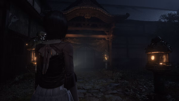Screenshot from FATAL FRAME II: Crimson Butterfly REMAKE showing a character approaching a dimly lit, eerie shrine at night.