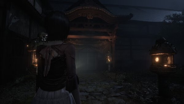 Screenshot from FATAL FRAME II: Crimson Butterfly REMAKE showing a character approaching a dimly lit, eerie shrine at night.