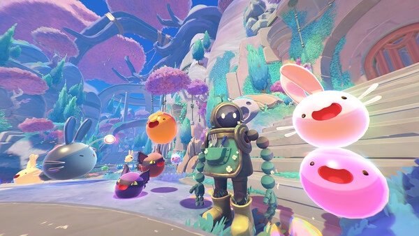 Screenshot from Slime Rancher 2 shows a rancher surrounded by colorful slimes and vibrant alien flora.