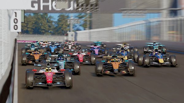 F1 25 screenshot: A crowded starting grid with multiple Formula 1 cars racing down a straight track surrounded by barriers.