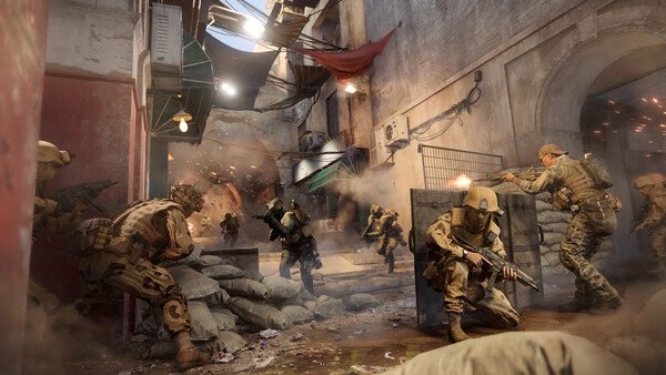 Battlefield 6 screenshot: Soldiers engage in intense urban combat, using barriers for cover amidst flying debris and gunfire.