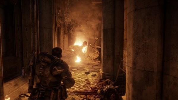 Gears of War: Reloaded screenshot showing a heavily armored soldier in a dimly lit corridor with rubble and fire in the background.
