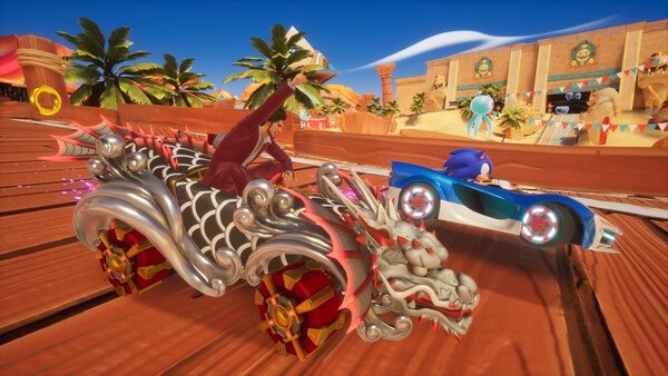Screenshot of Sonic Racing: CrossWorlds showing Sonic in a blue car racing against a dragon-themed vehicle on a sunny track.