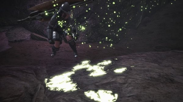 A screenshot from Monster Hunter: World showing a hunter investigating glowing monster tracks in a dark, rocky environment.
