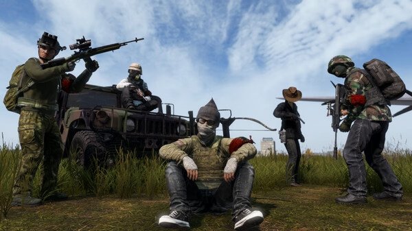 DayZ screenshot: Group of five armed players in military gear, some standing, one sitting, in grassy terrain with a vehicle behind them.