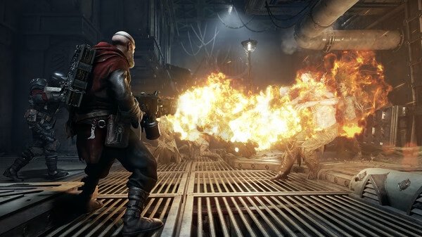 Warhammer 40,000: Darktide screenshot showing a player character firing a flamethrower at oncoming enemies in an industrial setting.